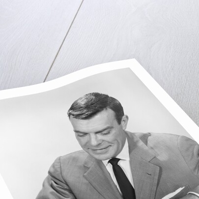 Smiling businessman at desk writing checks by Anonymous