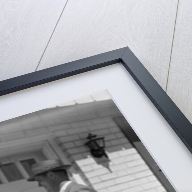 Salesman wearing suit tie hat carrying briefcase ringing suburban house doorbell by Anonymous