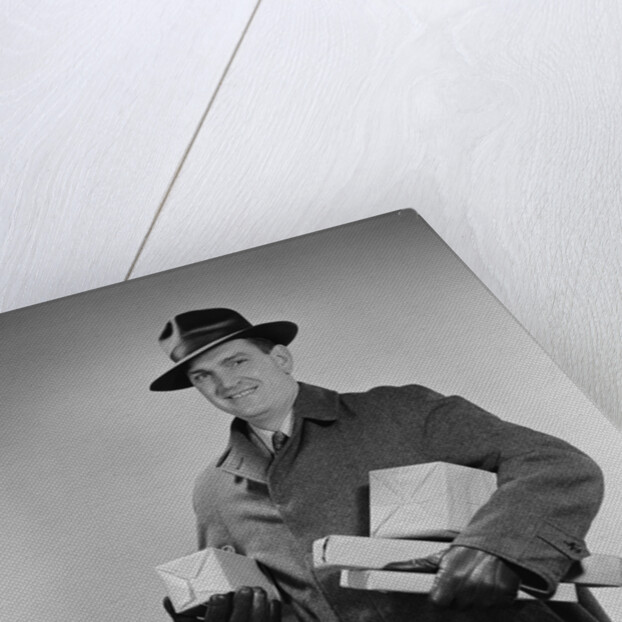 Man wearing winter coat hat gloves holding packages parcels by Anonymous