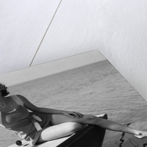 Woman wearing one piece bathing suit sitting on edge of boat by Anonymous