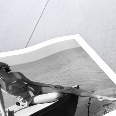 Woman wearing one piece bathing suit sitting on edge of boat by Anonymous