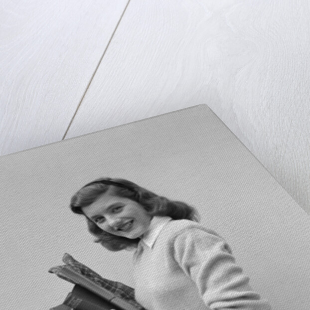 Smiling brunette teen student wearing sweater carrying school books by Anonymous