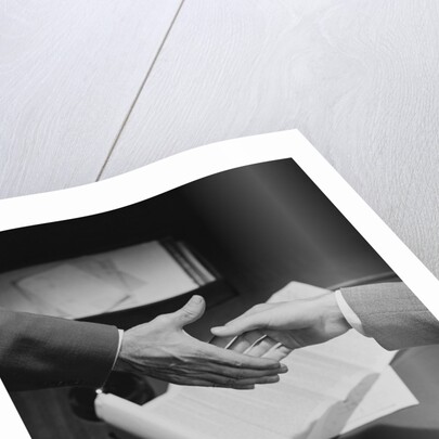 Close-up two male hands about to shake over desk with papers and telephone by Anonymous