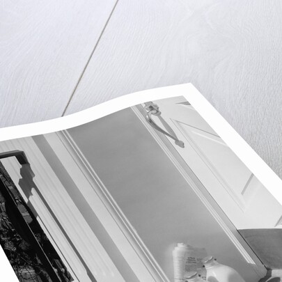 Glass milk bottles and newspaper by front door home delivery by Anonymous