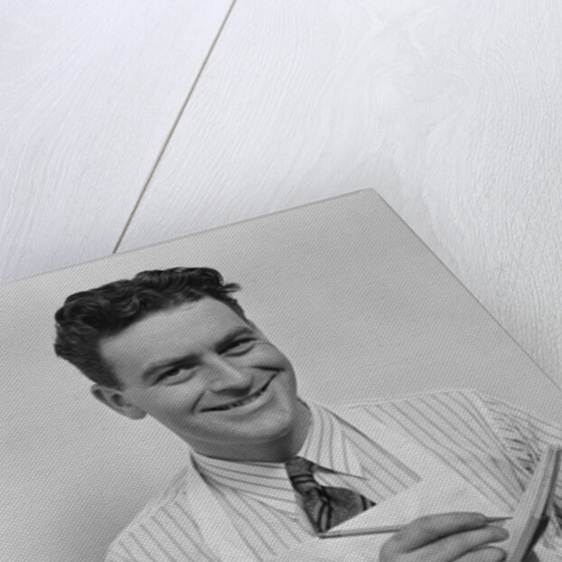 Smiling curly hair man wearing apron taking order with pencil and note pad by Anonymous
