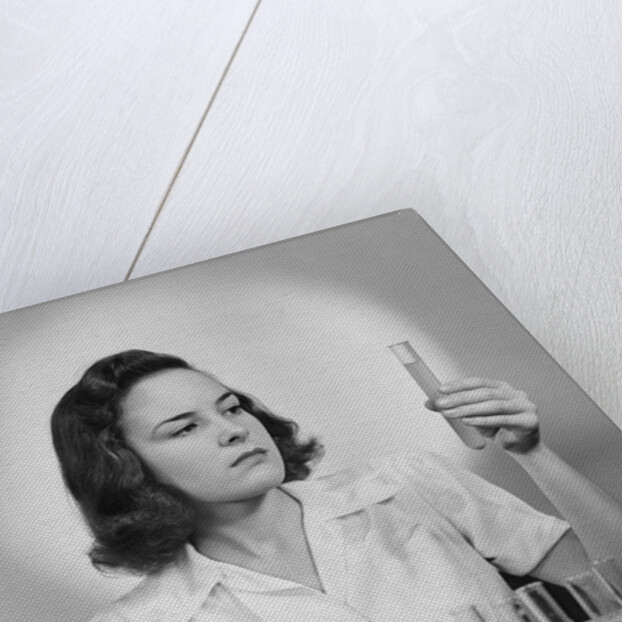 Young woman chemist holding up test tube by Anonymous