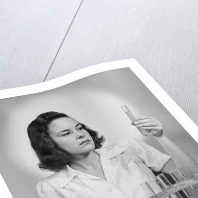 Young woman chemist holding up test tube by Anonymous