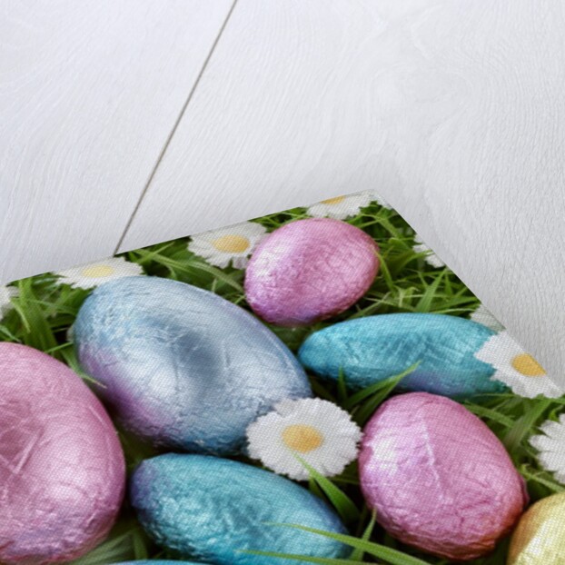 Chocolate Easter eggs in coloured foil in grass by Anonymous