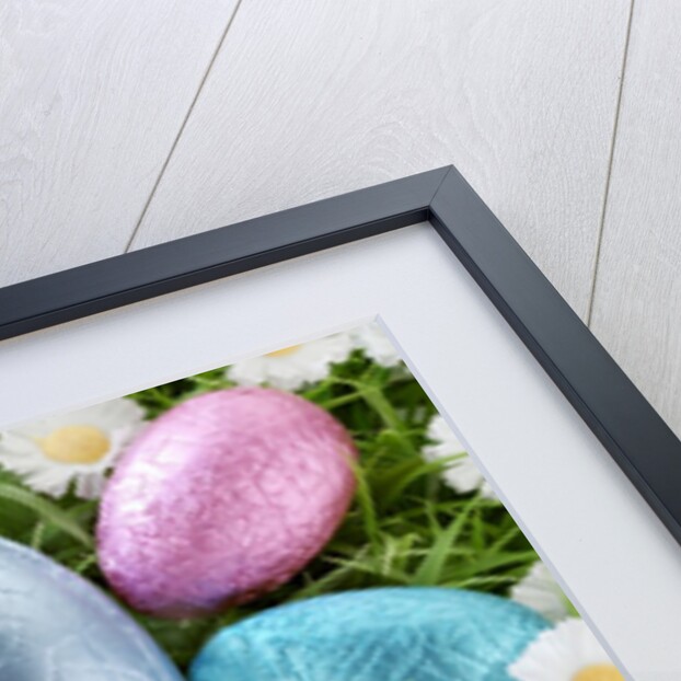 Chocolate Easter eggs in coloured foil in grass by Anonymous