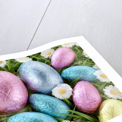 Chocolate Easter eggs in coloured foil in grass by Anonymous