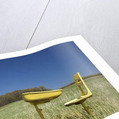 Abandoned school desk anc chairs in field by Anonymous