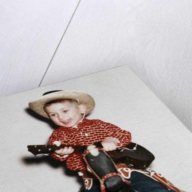 Little boy cowboy plays guitar while riding his horse, ca. 1956 by Anonymous
