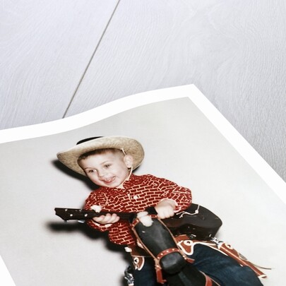 Little boy cowboy plays guitar while riding his horse, ca. 1956 by Anonymous
