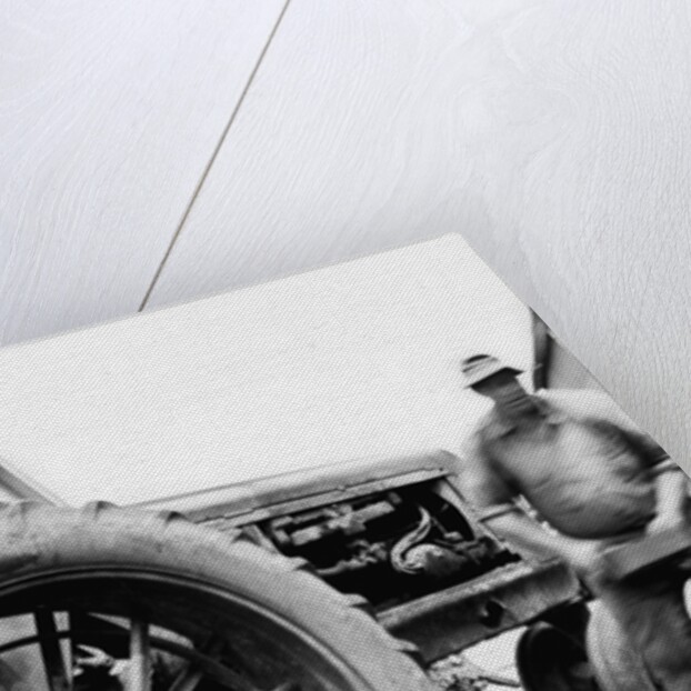 Farmer is a blur of activity working on his tractor, ca. 1938 by Anonymous