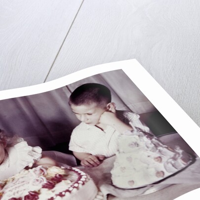 Brother watches his sister blow out candles on birthday cake, ca. 1956 by Anonymous