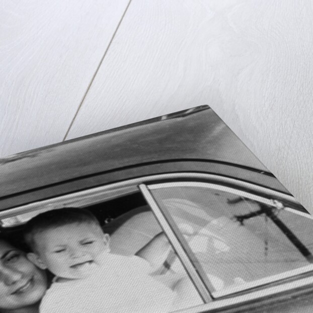 Mother holds crying son in her lap in car, ca. 1954 by Anonymous