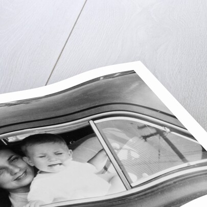 Mother holds crying son in her lap in car, ca. 1954 by Anonymous