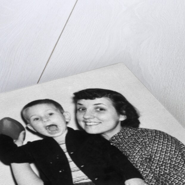 Little boy holding football with his mother, ca. 1955 by Anonymous