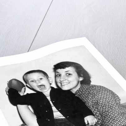 Little boy holding football with his mother, ca. 1955 by Anonymous