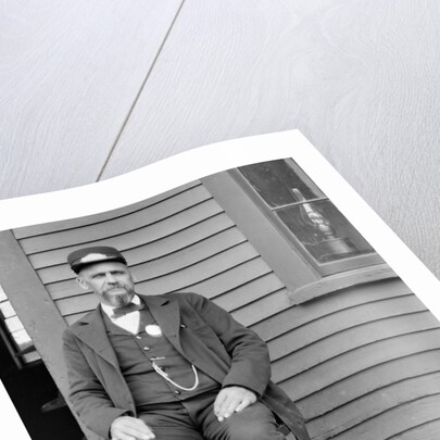 Station master sits at the train depot, ca. 1900. by Anonymous