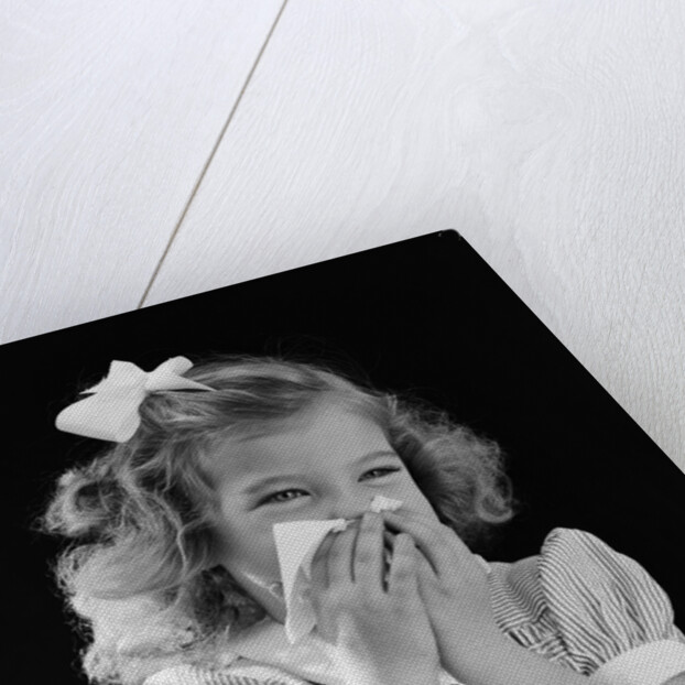 1940s little blond girl ribbon in hair holding tissue to nose sneezing by Anonymous