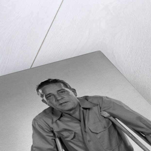 1960s man walking on crutches looking at camera by Anonymous