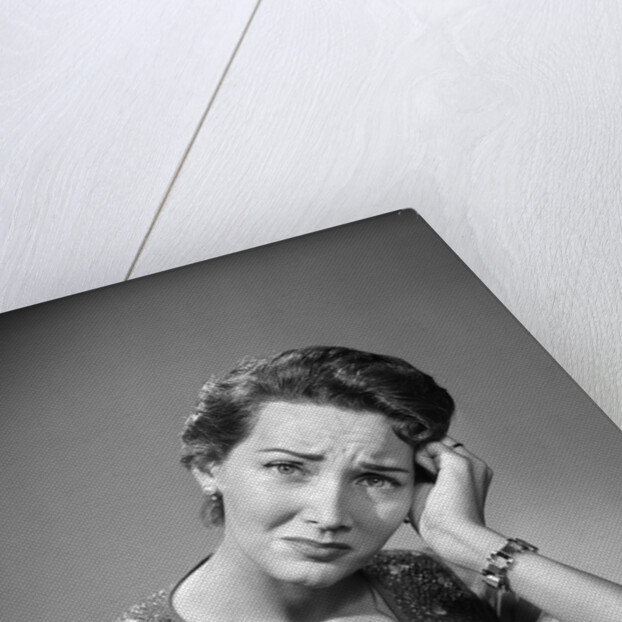 1950s housewife woman in print apron hand up to temple headache pain sad depressed facial expression worried serious looking at camera by Anonymous