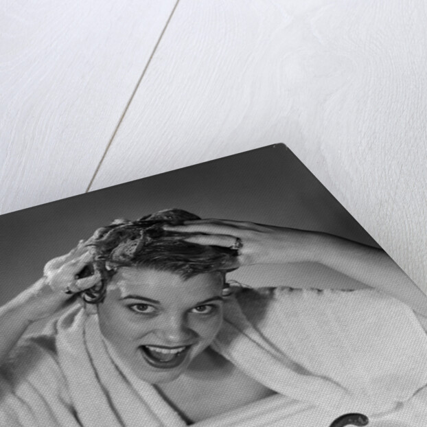 1950s smiling woman washing shampooing hair in sink looking at camera by Anonymous