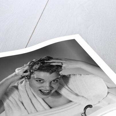 1950s smiling woman washing shampooing hair in sink looking at camera by Anonymous