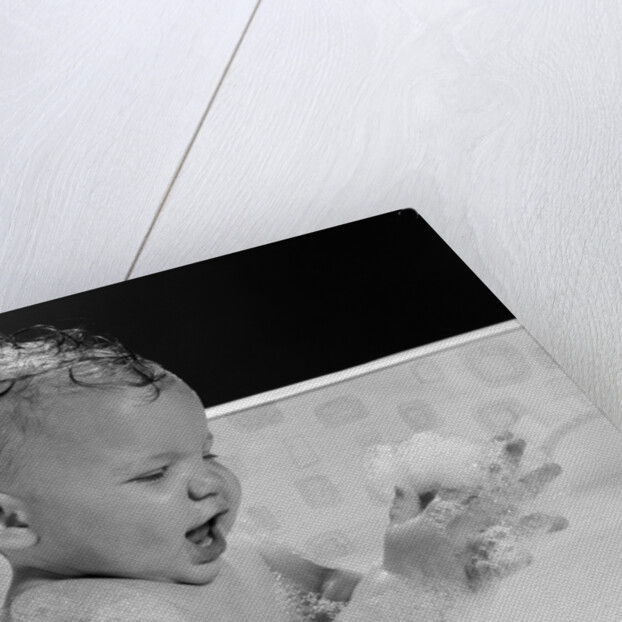 1960s baby in bathtub playing with suds indoor by Anonymous