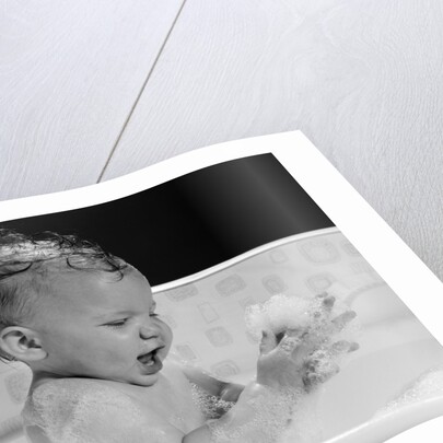 1960s baby in bathtub playing with suds indoor by Anonymous