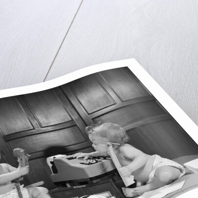 1960s 2 babies in diapers one on chair with telephone other on floor with adding machine pencil behind ear by Anonymous