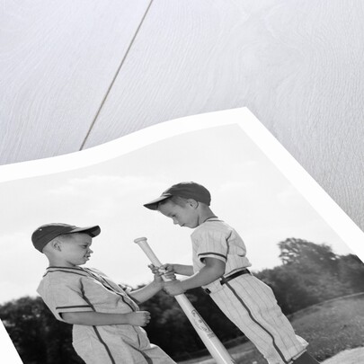 1960s two boys in baseball uniforms choosing sides by getting the upper hand on a bat by Anonymous