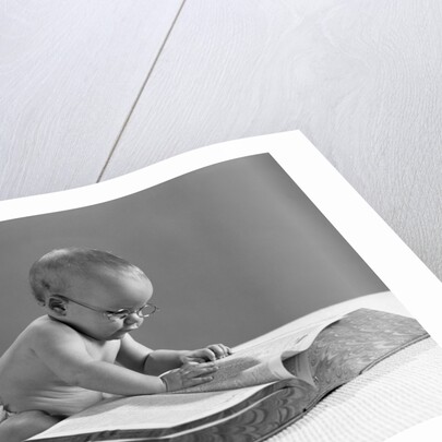 1960s baby wearing glasses looking for a word in big dictionary by Anonymous