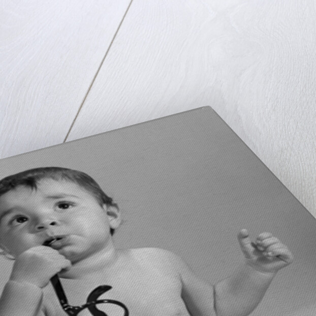 1960s baby in diaper chewing on eyeglasses by Anonymous