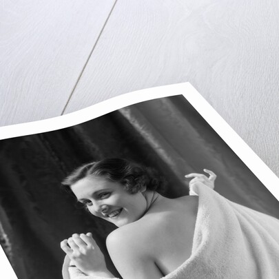 1930s smiling brunette woman looking over shoulder drying back with towel looking at camera by Anonymous