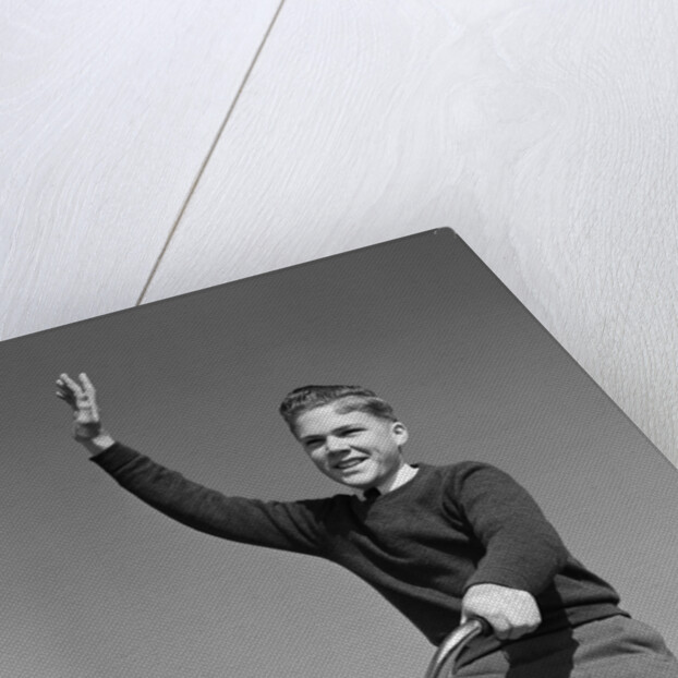 1940s 1950s smiling boy riding bike waving arm in air by Anonymous