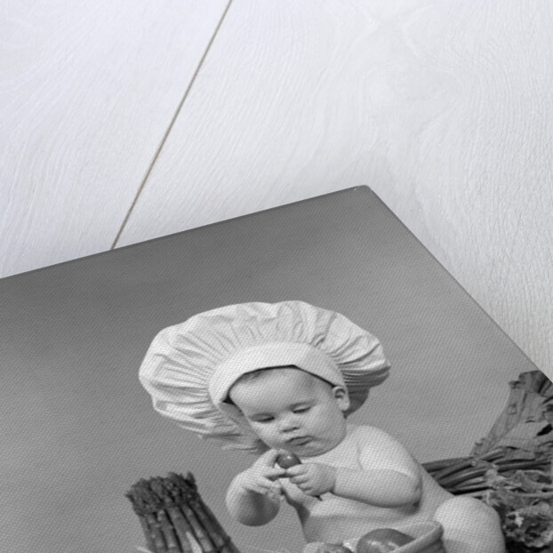 1950s 1960s baby wearing chef hat toque bowl and raw vegetables making a salad by Anonymous