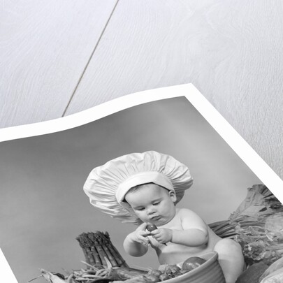 1950s 1960s baby wearing chef hat toque bowl and raw vegetables making a salad by Anonymous