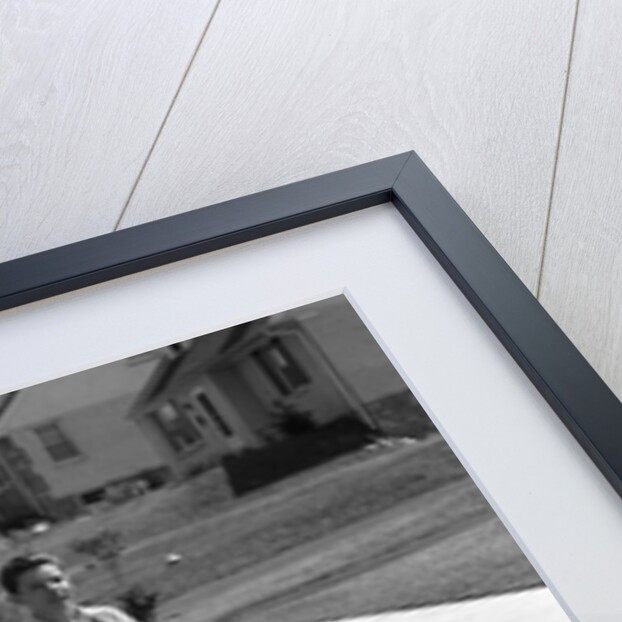 1950s teen boy girl couple riding bikes down residential street by Anonymous