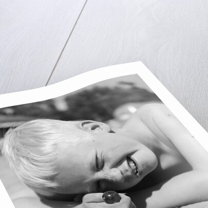 Boy crouching shooting marbles concentration by Anonymous