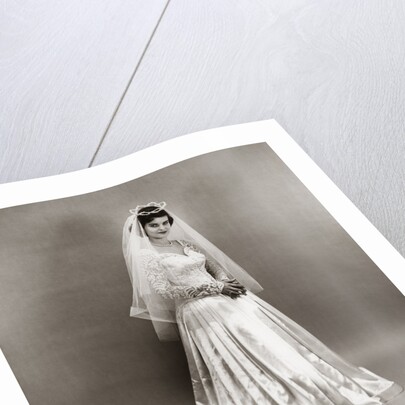 1950s full length portrait bride standing wearing satin and lace wedding gown veil and tiara looking at camera by Anonymous