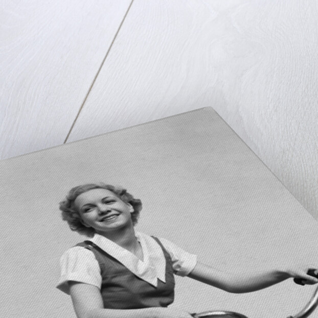 1930s smiling blonde woman riding bicycle looking at camera by Anonymous