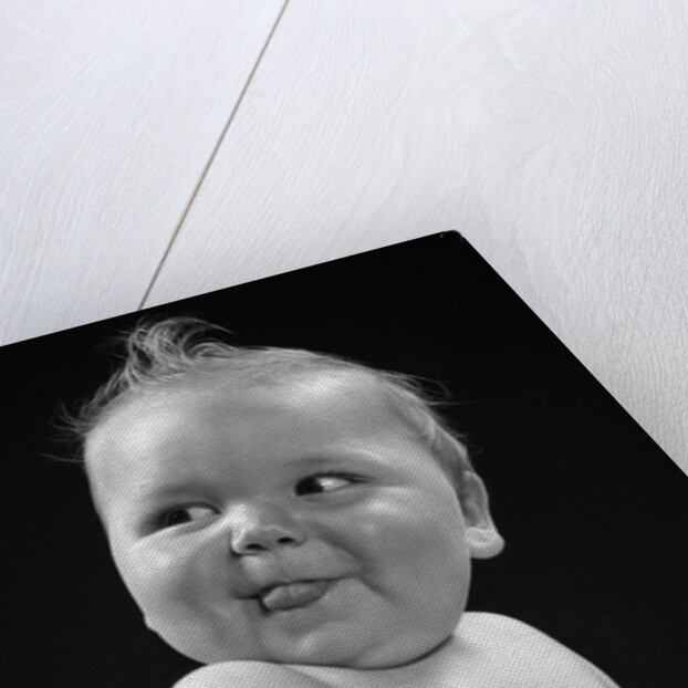 1950s 1940s baby in high chair head turned to one side with tongue sticking out funny facial expression by Anonymous