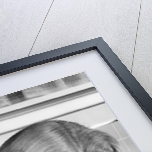 1950s mother woman bending over baby lying on layette holding hands talking by Anonymous