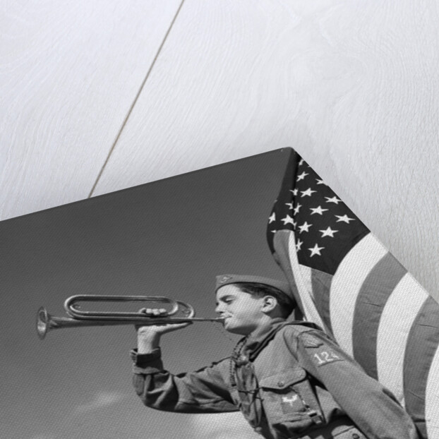 1950s profile of boy scout in uniform standing in front of 48 star american flag blowing bugle by Anonymous