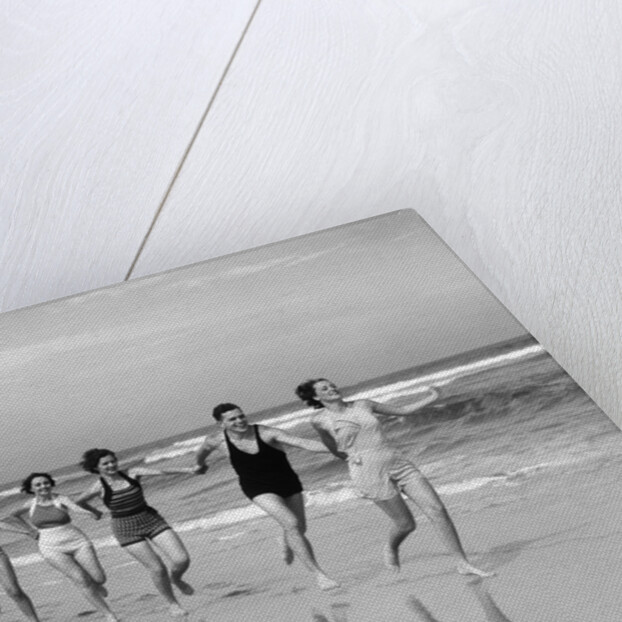 1930s four women and one man running on beach holding hands by Anonymous