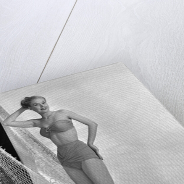 1950s glamour girl looking at camera posed in studio draped in fishing net wearing two piece bathing suit by Anonymous