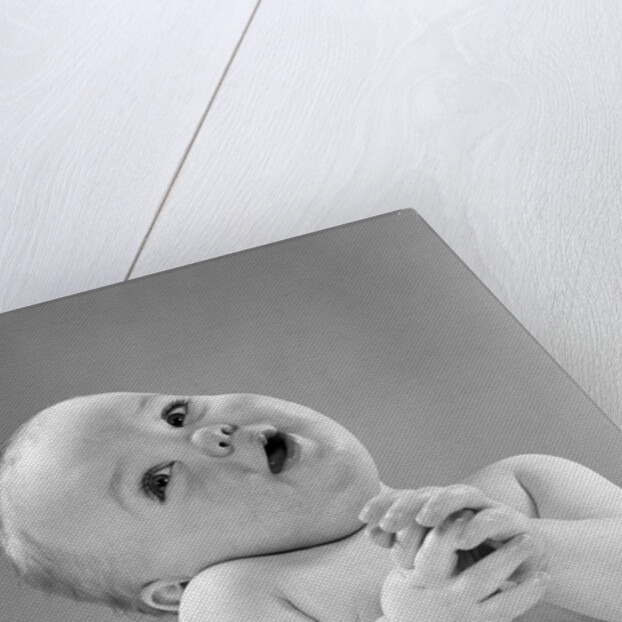 1950s baby in diaper head to one side arms hands clasped in front by Anonymous