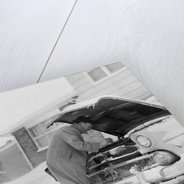 1950s man winter driveway trying to start fix car hood up by Anonymous